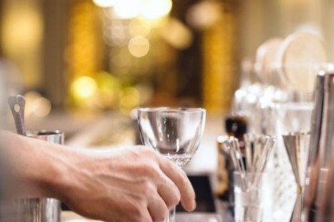 Hand placing an empty wine glass on a bar counter.