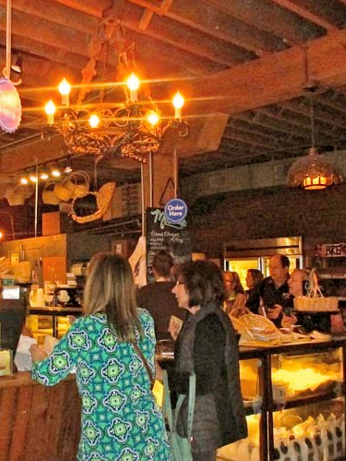 People ordering at a rustic cafe counter with warm lighting and wooden decor.
